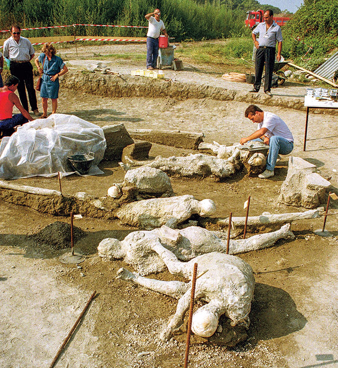enlargeable photo of scientists examining stone casts of people