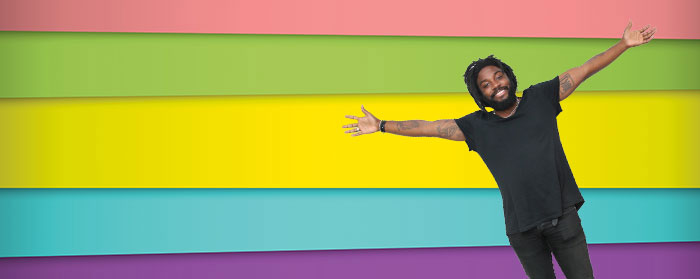 a man smiling with arms wide open in front of a colorful banner