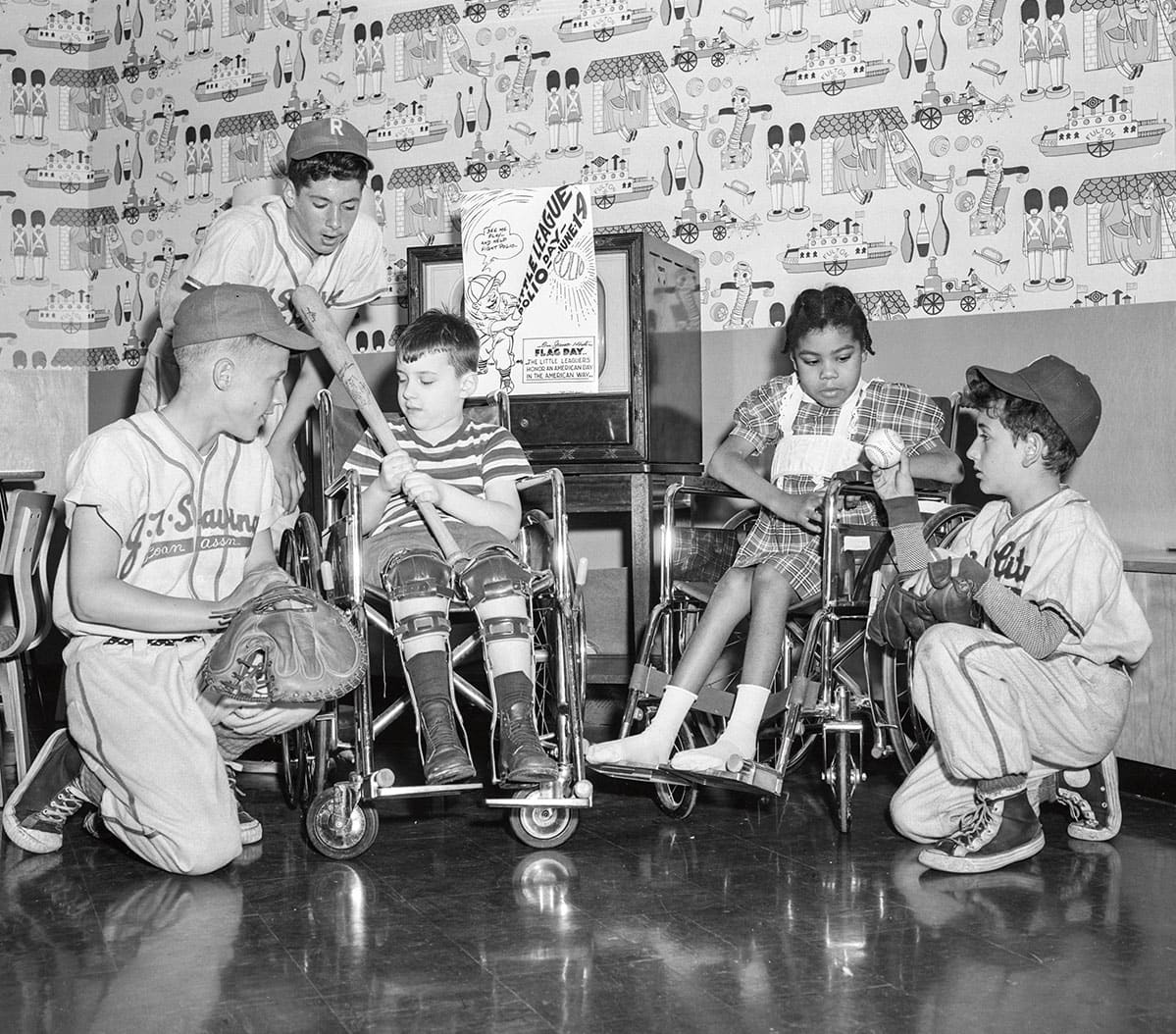 black and white photo of two children in wheelchairs with little league baseball players