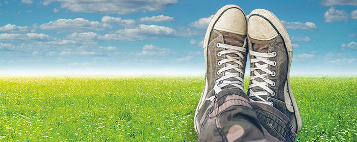 image of someone crossing their feet in a meadow with clouds in the sky