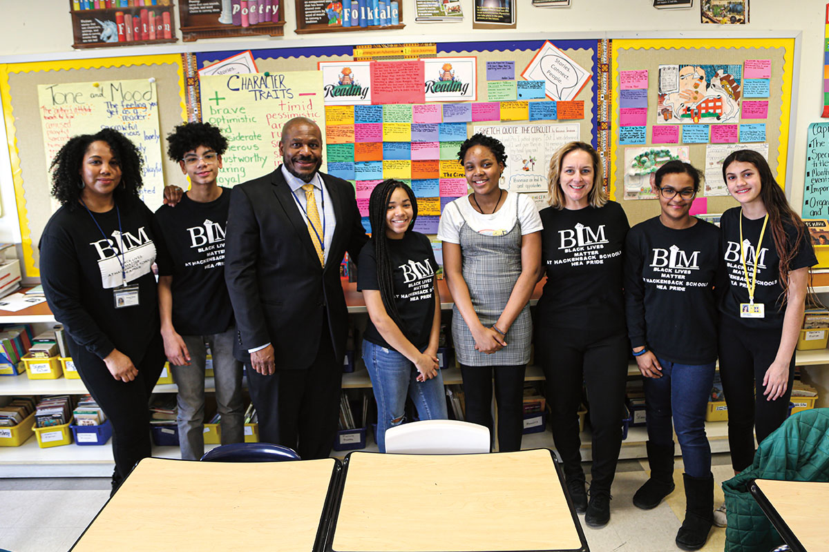 Students and teachers wearing BLM shirts while a man in a suit poses with them