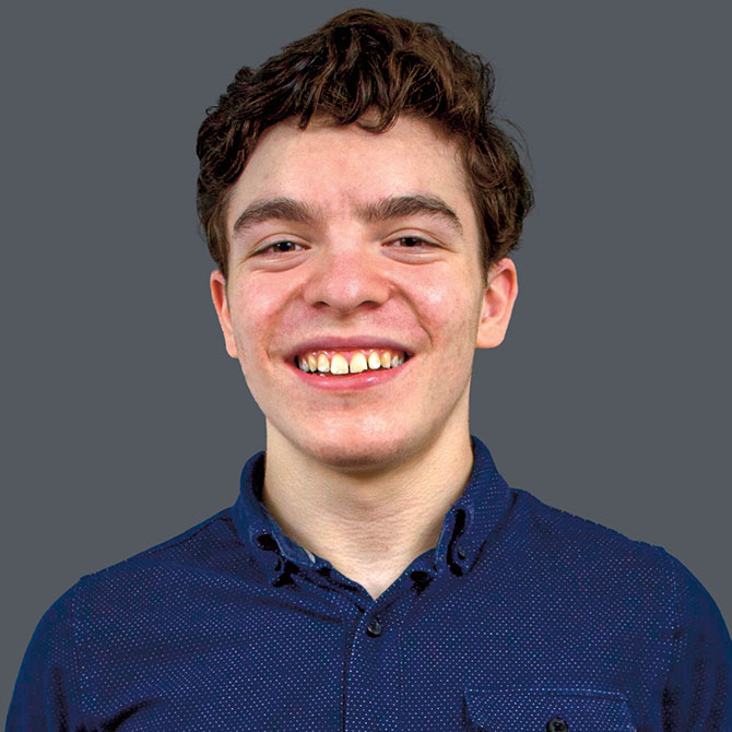 A smiling young man with brown hair wearing blue shirt