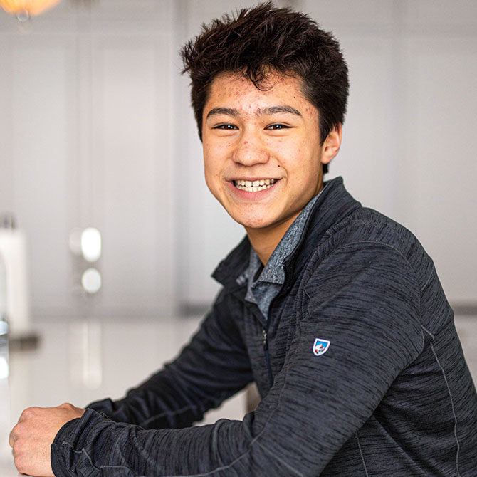A boy wearing a gray lightweight workout jacket smiling