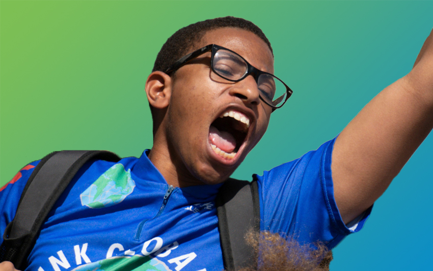 A young man wearing glasses shouting passionately with his hand in the air