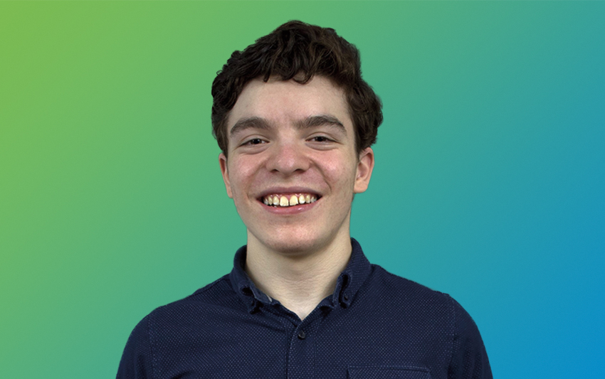 A smiling young man with brown hair wearing blue shirt