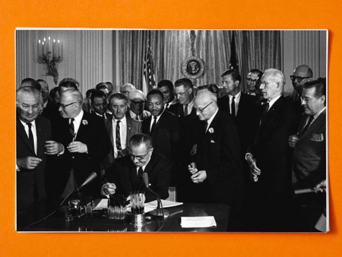 Martin Luther King and other men watching the Civil Rights Act being signed and passed