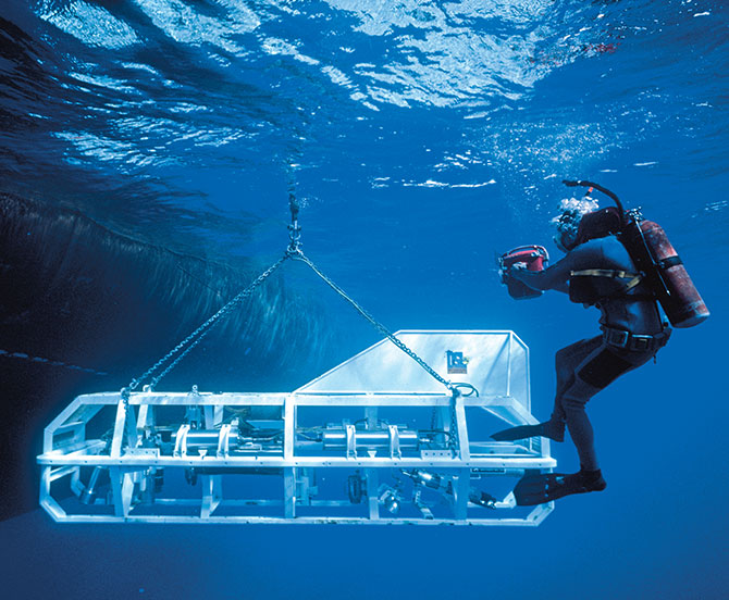 Enlargeable photo of a diver swimming beside a see-through submarine being lowered into the water