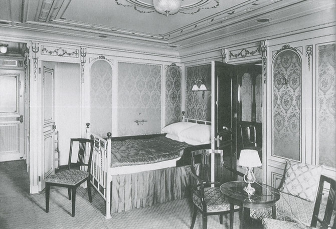A black and white photo of a bedroom with a small sitting area