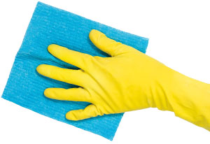 A yellow gloved hand with a blue cleaning cloth