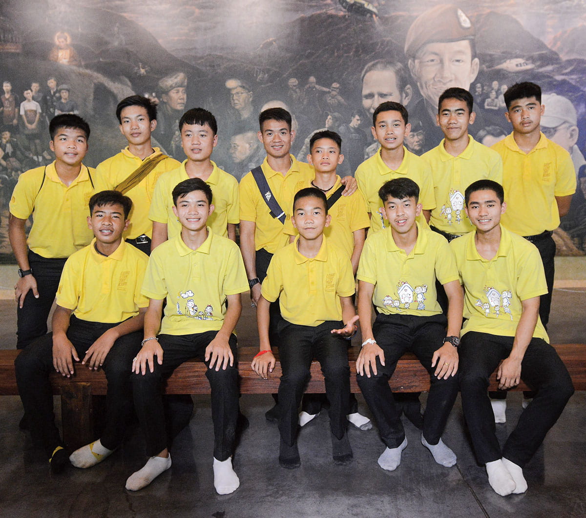 A group of boys in yellow shirts posing for a picture