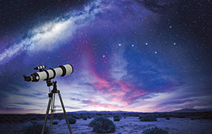 Image of a telescope with the starry milky way in the background