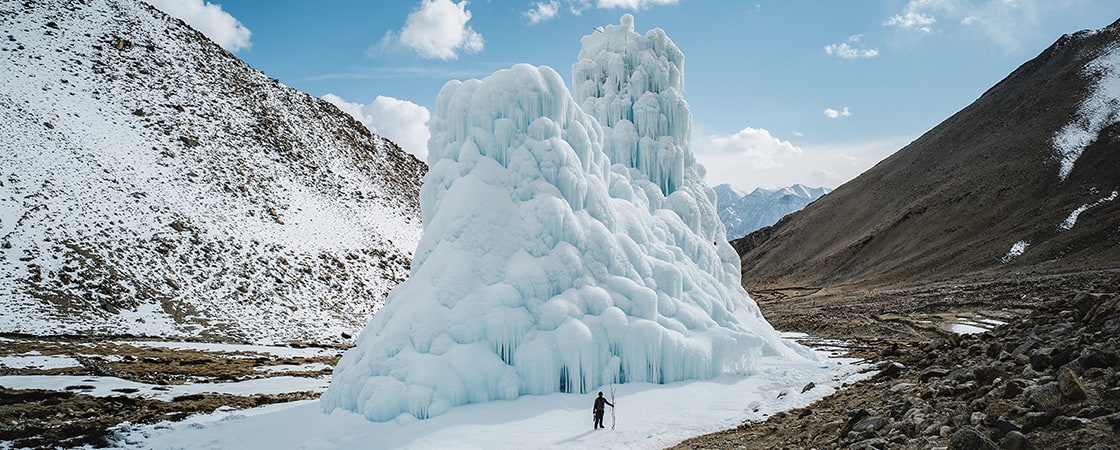 Photo of a person standing in front of a huge ice tower