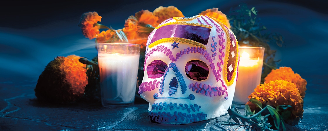 Image of a beautifully decorated skull surrounded by candles and flowers