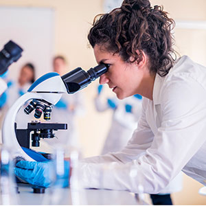 A scientist looking into a microscope at an organism