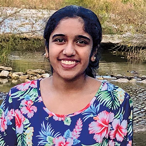 A girl wearing a floral shirt smiling brightly for the photo